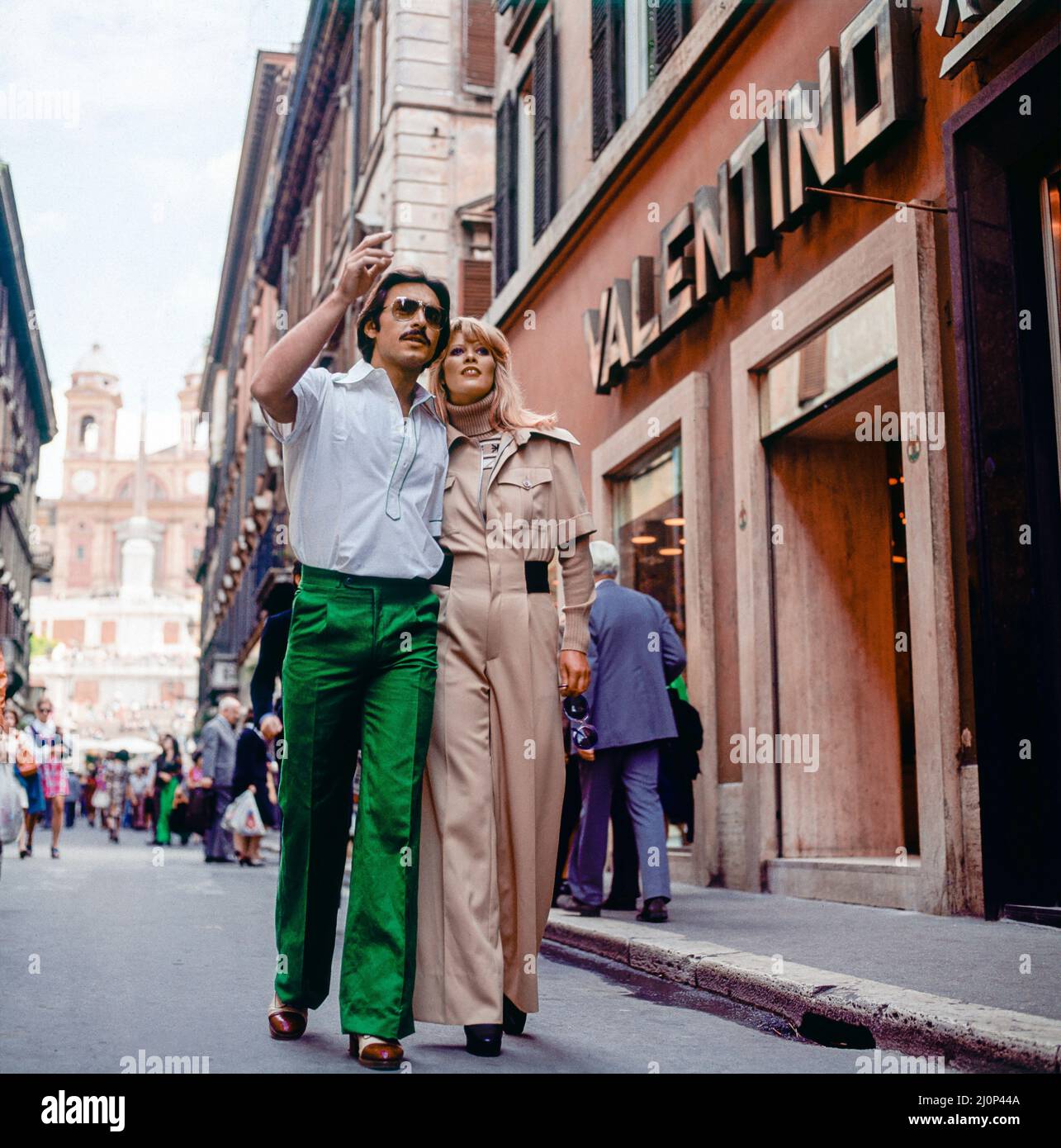 Vintage Rome 1970s, couple élégant se promener par le magasin de mode Valentino, rue commerçante via dei Condotti, Italie, Europe, Banque D'Images