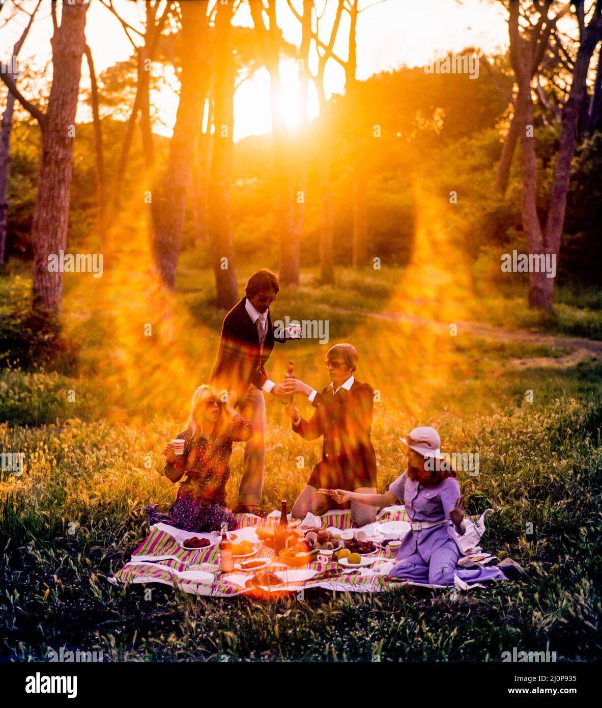 Vintage Italie 1970s, 2 couples d'amis gais ayant un pique-nique au coucher du soleil, lumière solaire, fin d'après-midi, campagne romaine, Lazio, Europe, Banque D'Images