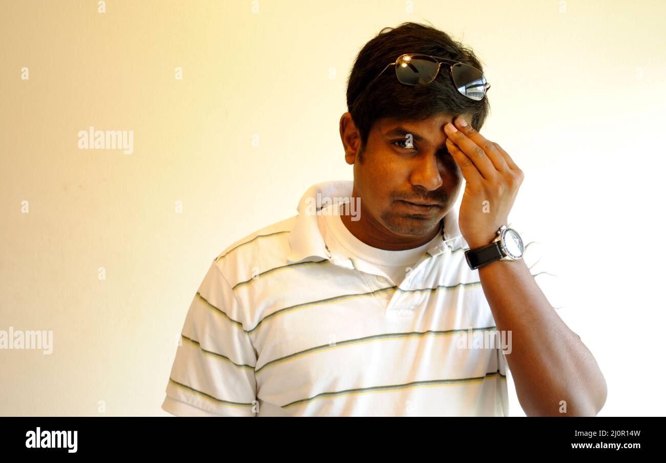 Mâle indien posant avec une main sur un oeil avec un verre solaire avec un fond blanc Banque D'Images