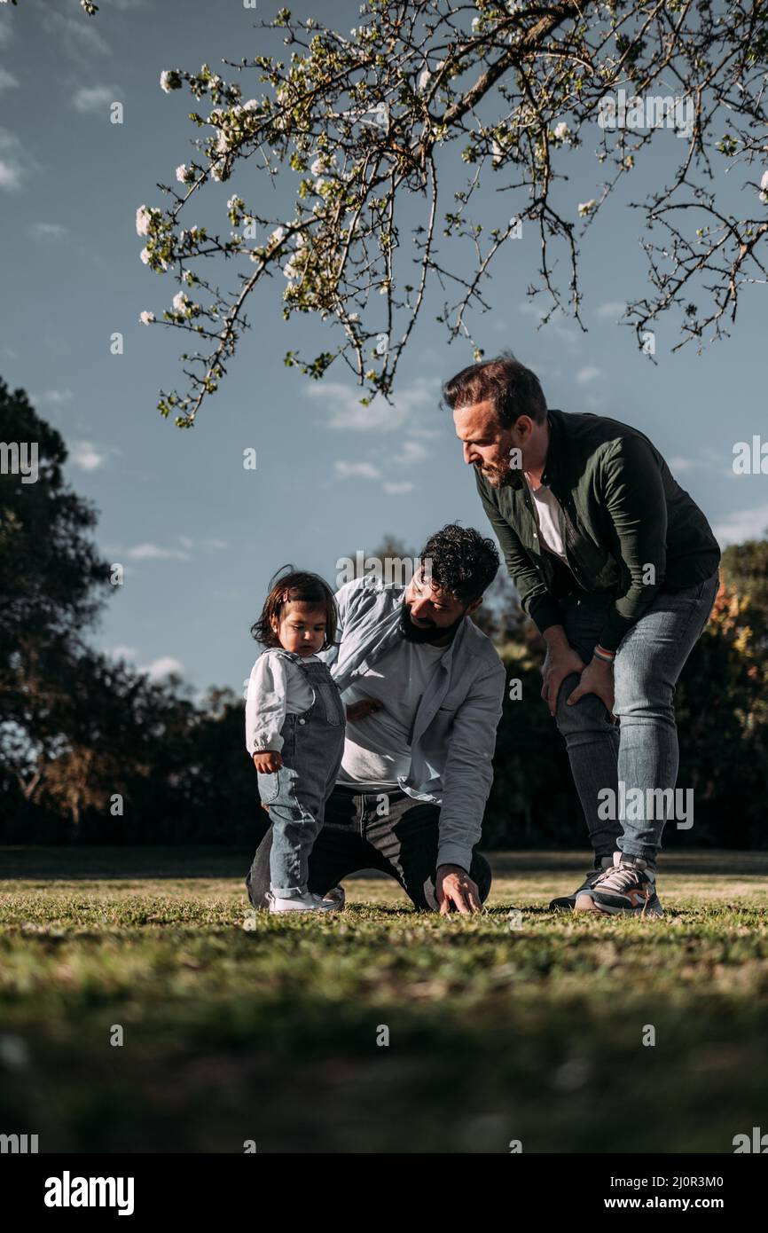 Couple gay masculin enseignant leur jeune fille dans un parc. Concept de famille moderne. Verticale. Banque D'Images
