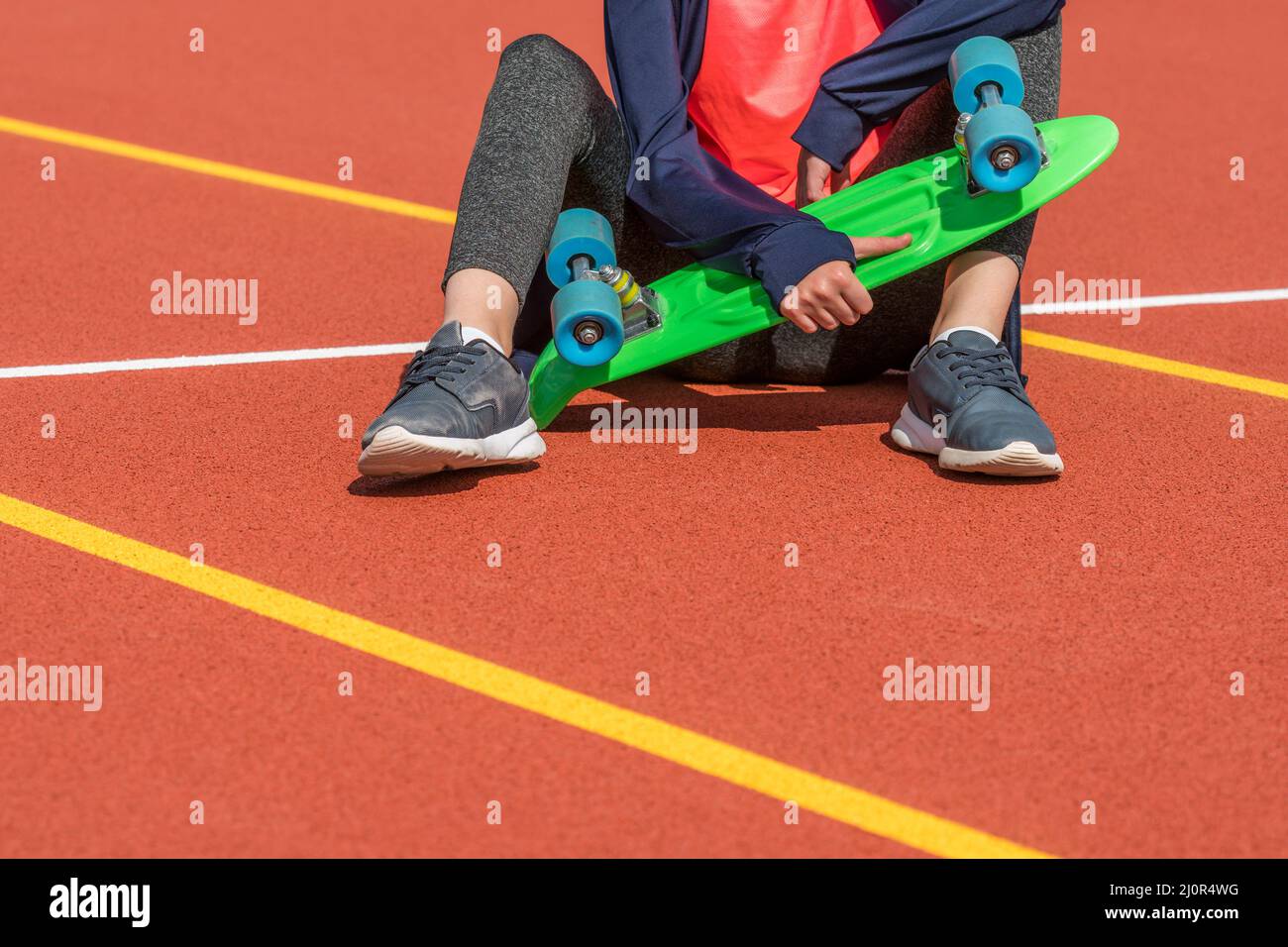 Petite fille assise tenant un panneau de sou en plastique vert Banque D'Images