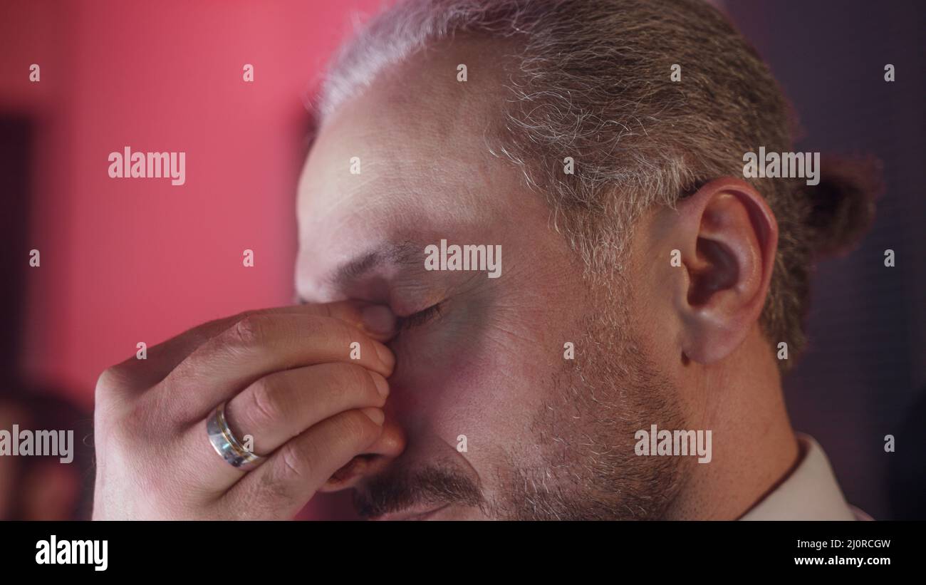 Gros plan extrême d'un employé de bureau d'âge moyen barbu. Regarder l'ordinateur trop et la fatigue oculaire. Banque D'Images