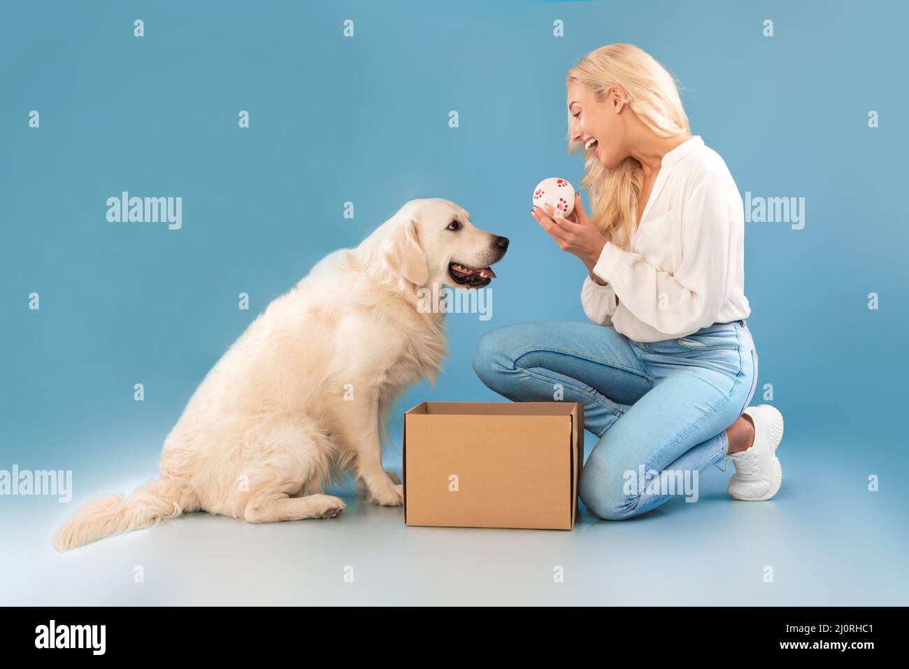 Jeune femme excitée jouant avec le chien tenant le ballon Banque D'Images