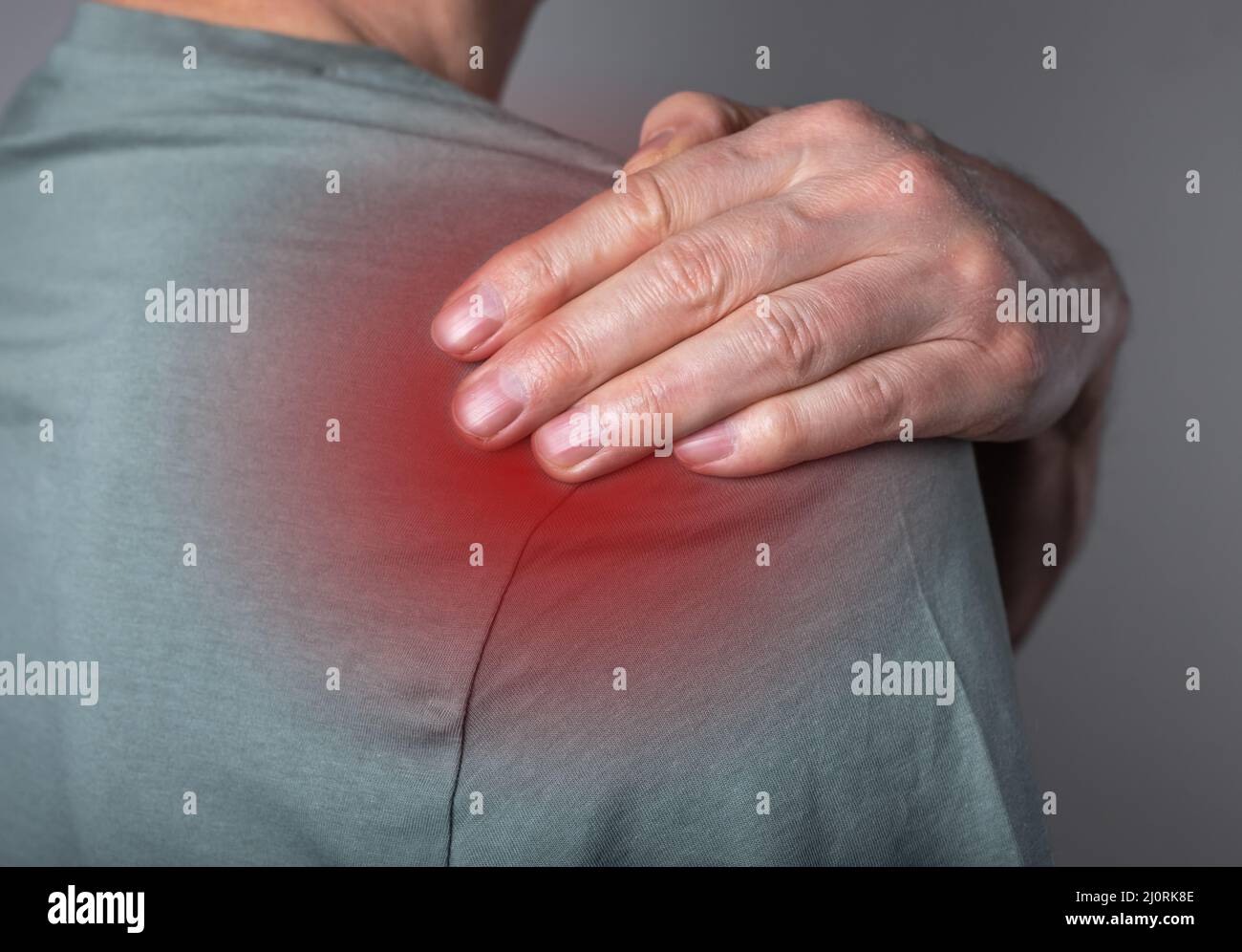 Homme souffrant de douleurs à l'épaule. Point de déclenchement. Main tenant l'épaule avec un point rouge de près. Problèmes de santé, concept de médecine. Photo de haute qualité Banque D'Images