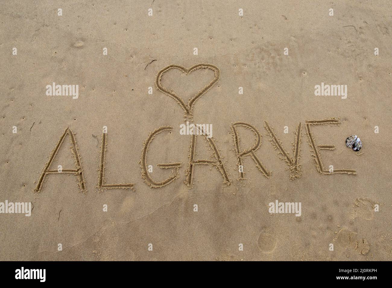 Mot Algarve écrit dans le sable avec un coeur Banque D'Images