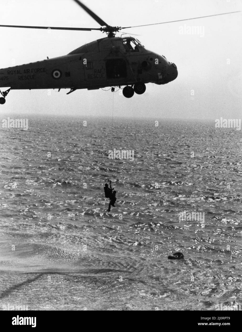Un hélicoptère de recherche et de sauvetage Wessex HAS1 de Westland se treuils à bord d'un des deux garçons s'envola en mer à Bridlington tandis que son ami s'accroche à l'gonflable. 15th août 1983 Banque D'Images