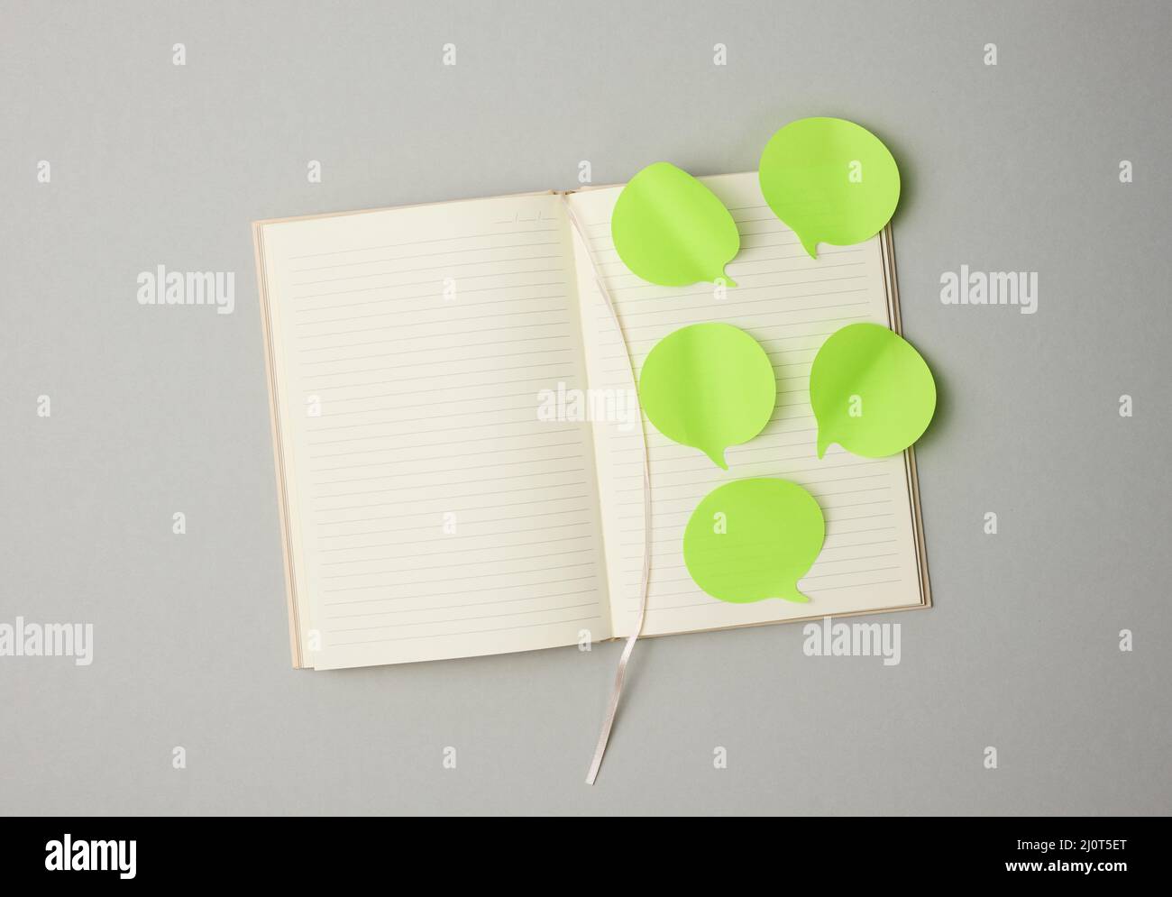 Papier vierge autocollants verts en forme de nuage collé sur des feuilles blanches d'un bloc-notes, fond gris Banque D'Images
