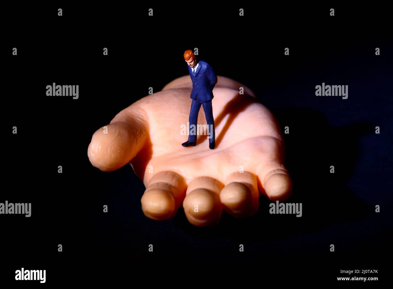 Figure miniature homme debout sur une fausse main, la santé mentale dans le besoin d'un concept de main d'aide Banque D'Images