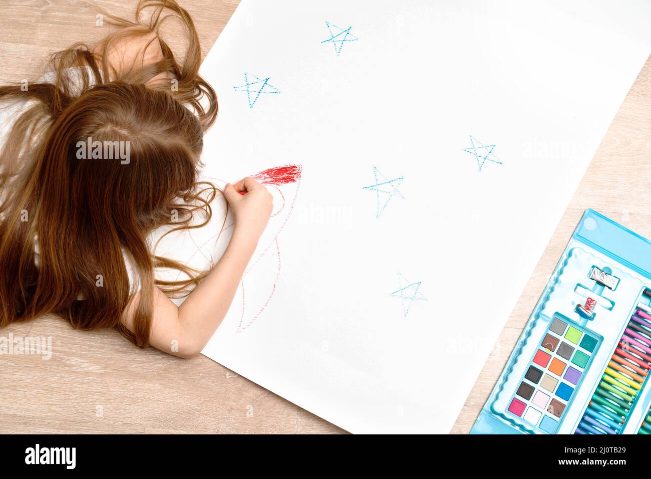 Un petit garçon dessine une photo sur le sol dans sa chambre, vue de dessus. Art des enfants , école à domicile et concept de créativité. Photo de haute qualité. Banque D'Images