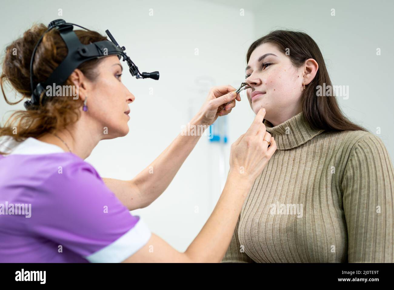 Otolaryngologie concept. Femme positive otorhinolaryngologiste vérifiant le nez avec l'otoscope de son patient à l'hôpital. Conge nasal Banque D'Images