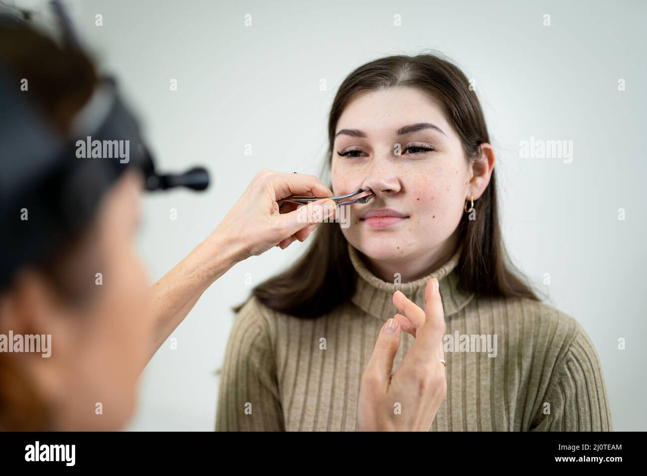 Otolaryngologie concept. Femme positive otorhinolaryngologiste vérifiant le nez avec l'otoscope de son patient à l'hôpital. Conge nasal Banque D'Images