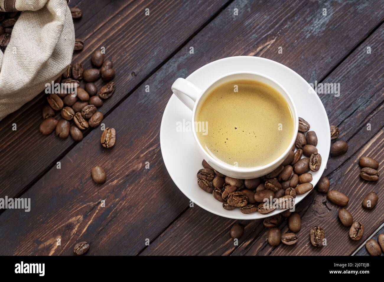 Une tasse de café chaud avec des grains de café sur une table en bois rustique Banque D'Images