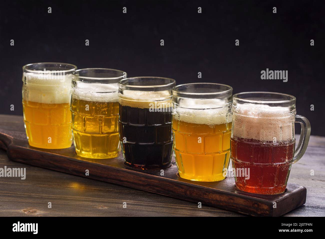 Ensemble de dégustation de différents types de bière sur une table sur fond sombre Banque D'Images