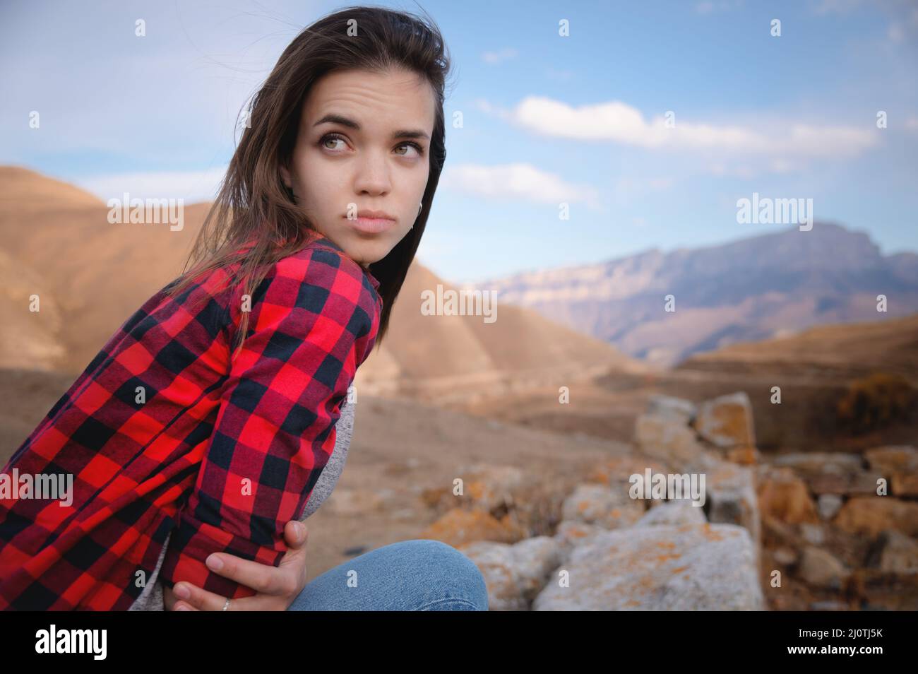 Portrait de la jeune femme caucasienne attrayante appréciant dans les montagnes sur le fond de rochers épiques regardant loin Banque D'Images