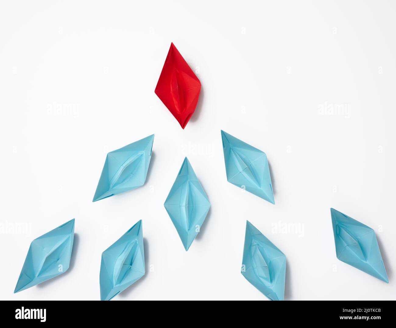 Groupe de bateaux en papier sur fond blanc. Concept d'un leader fort dans une équipe, manipulation des masses, suivant de nouvelles pers Banque D'Images