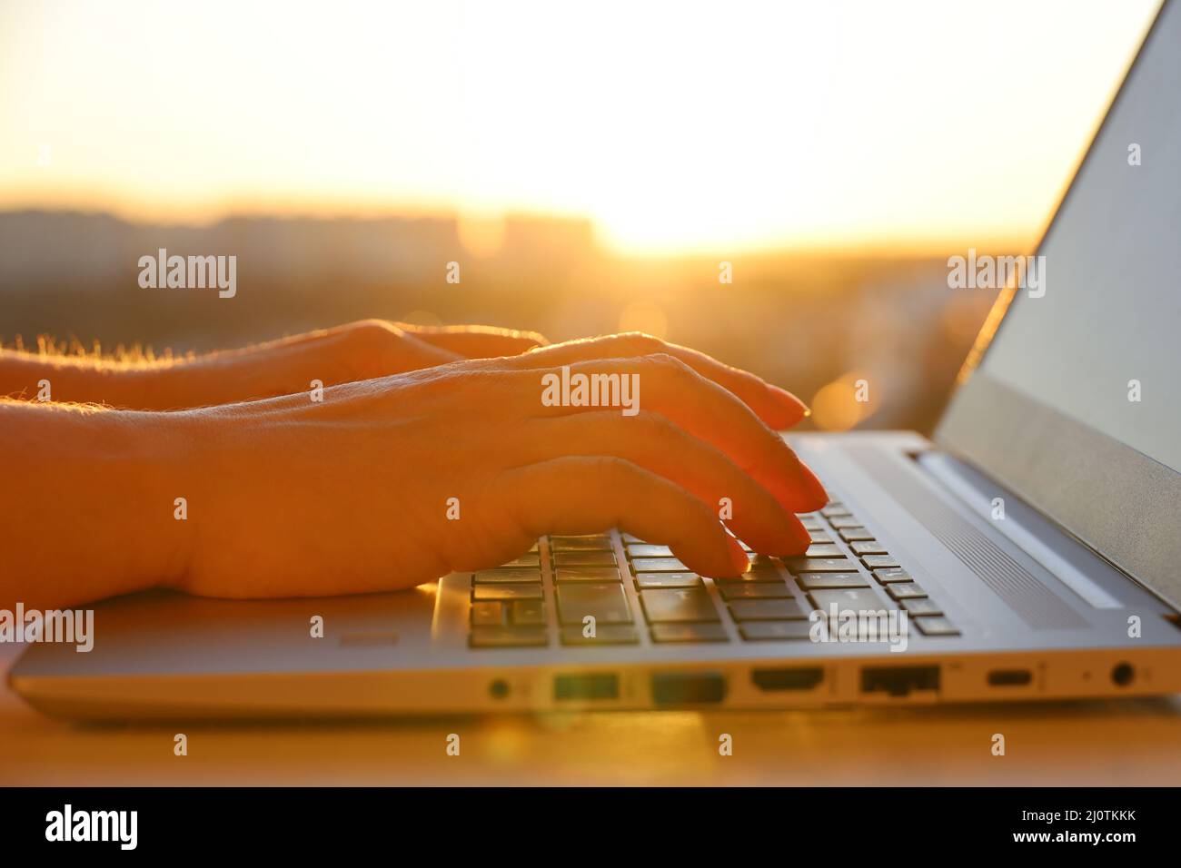Les femmes ont les mains sur le clavier de l'ordinateur portable près de la fenêtre avec le soleil. Espace de travail confortable, concept de travail au bureau ou à la maison Banque D'Images