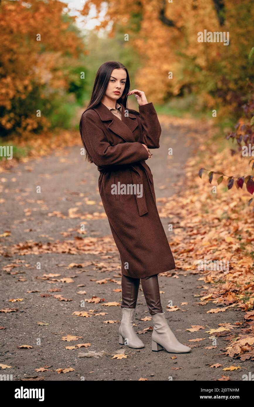 Jeune belle femme en manteau long sur la voie de campagne en automne Banque D'Images