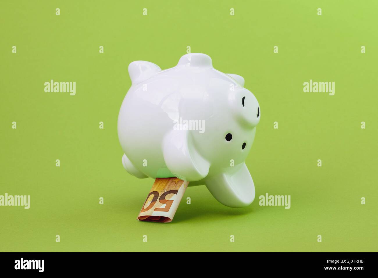 La banque de piggy avec cinquante euros tombe sur le fond vert Banque D'Images