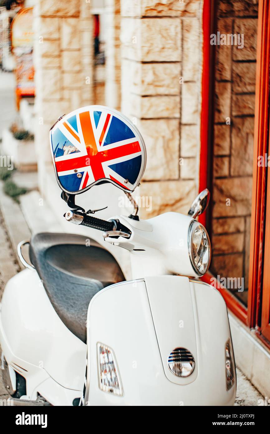 Un scooter blanc avec un casque aux couleurs du drapeau britannique se trouve près d'un bâtiment en pierre Banque D'Images