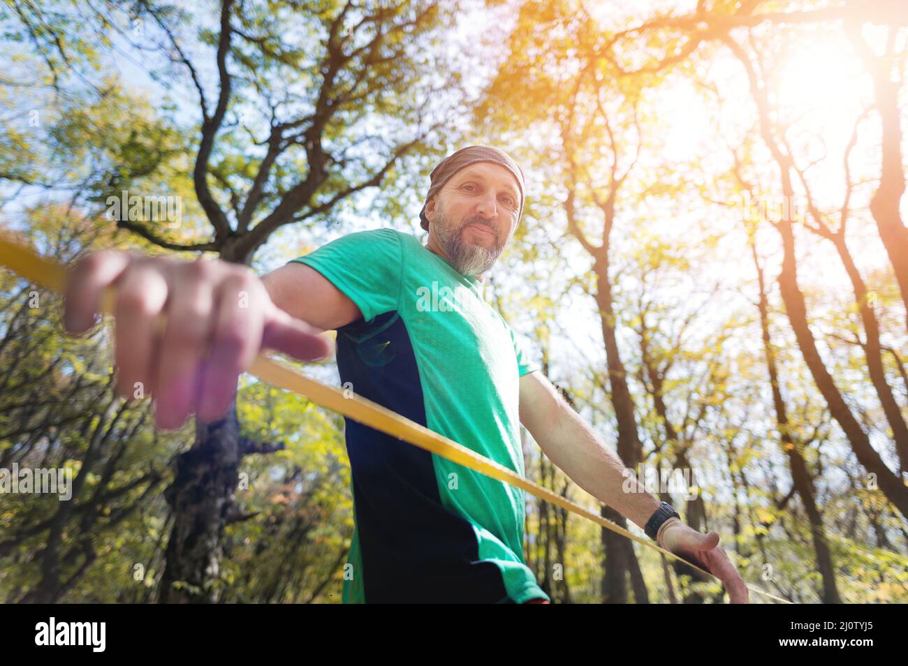 Portrait d'un sportif mûr avec une barbe à côté d'une ligne de détente tendue dans la forêt d'automne dans l'après-midi. Le concept de Banque D'Images