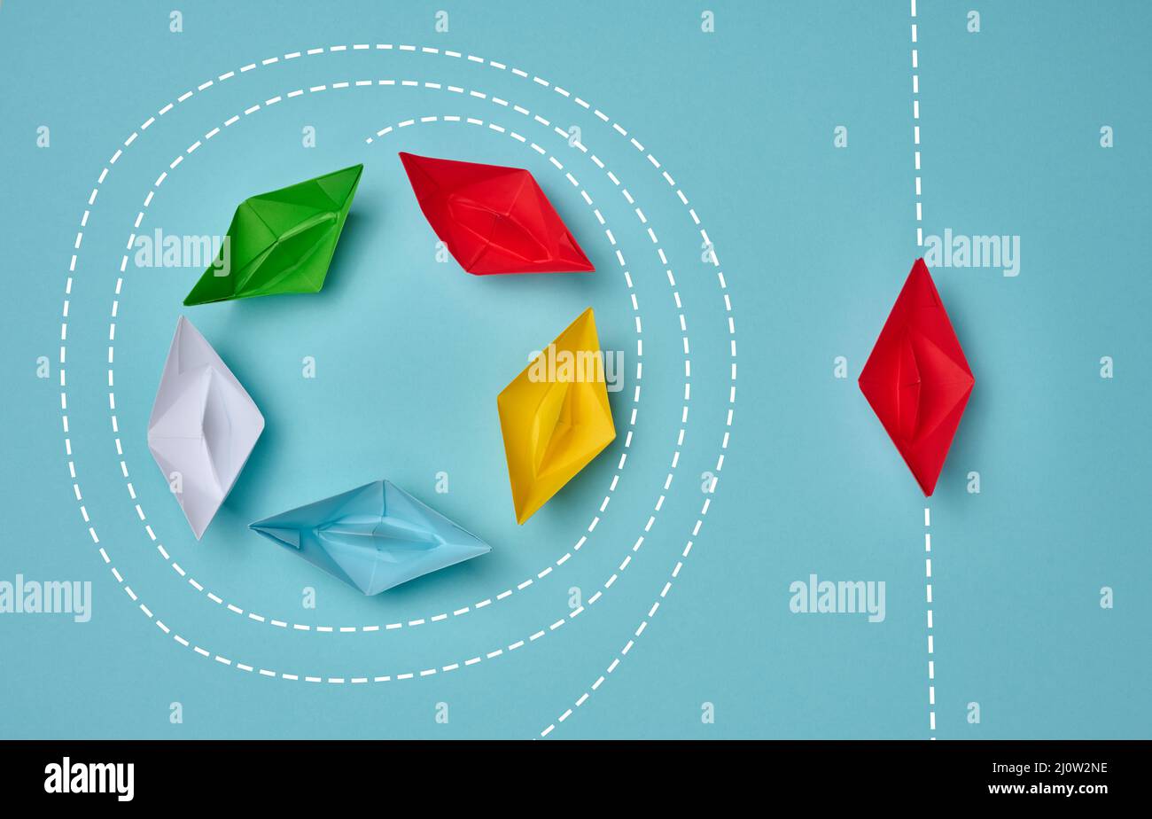 Un groupe de bateaux en papier flotte dans un cercle, un autre rouge flotte en ligne droite. Concept de leader fort, vision différente, stron Banque D'Images