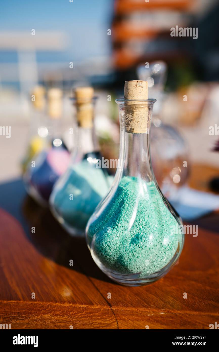 Des bouteilles de verre avec du sable coloré sont sur la table Banque D'Images