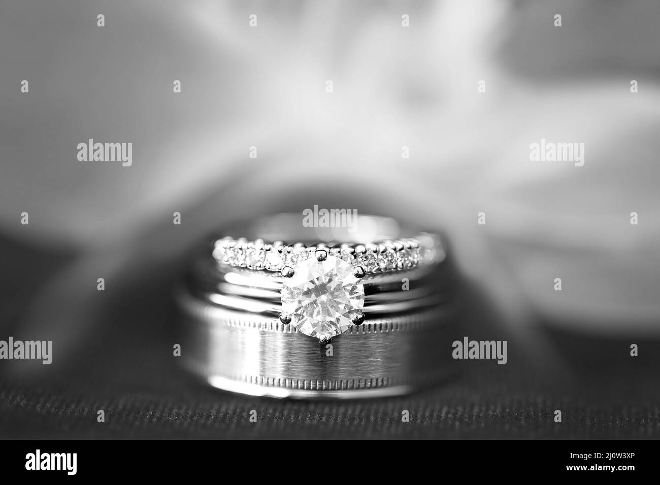 Anneaux de mariage empilés devant une fleur d'orchidée floue Banque D'Images