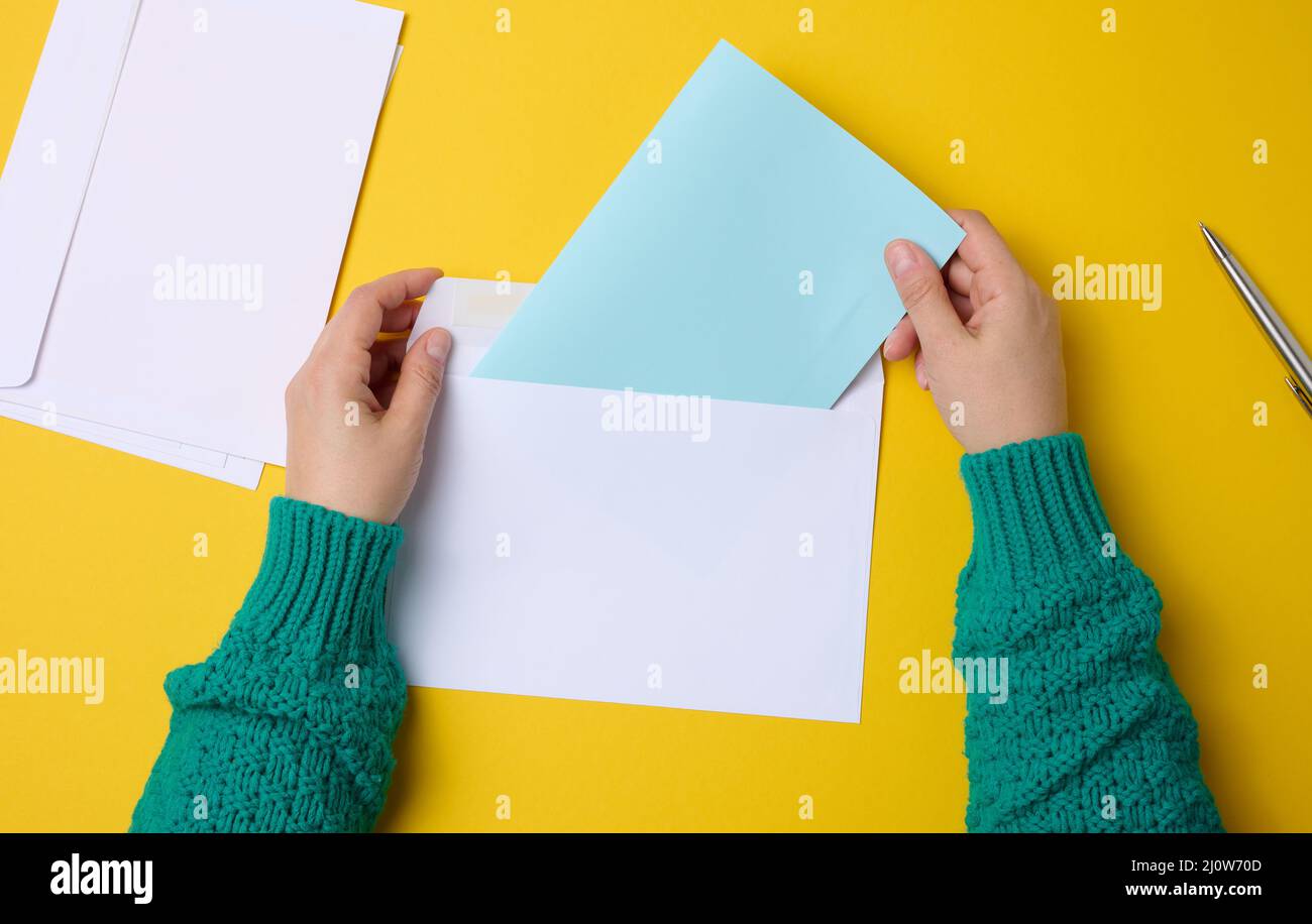 Main femelle pour les enveloppes en papier blanc sur fond orange, vue de dessus. Envoi et réception de correspondance Banque D'Images