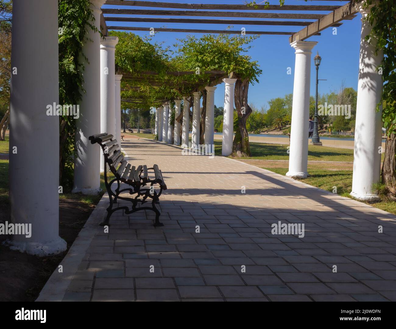 Banc en bois avec colonnes blanches dans un parc de la ville Banque D'Images