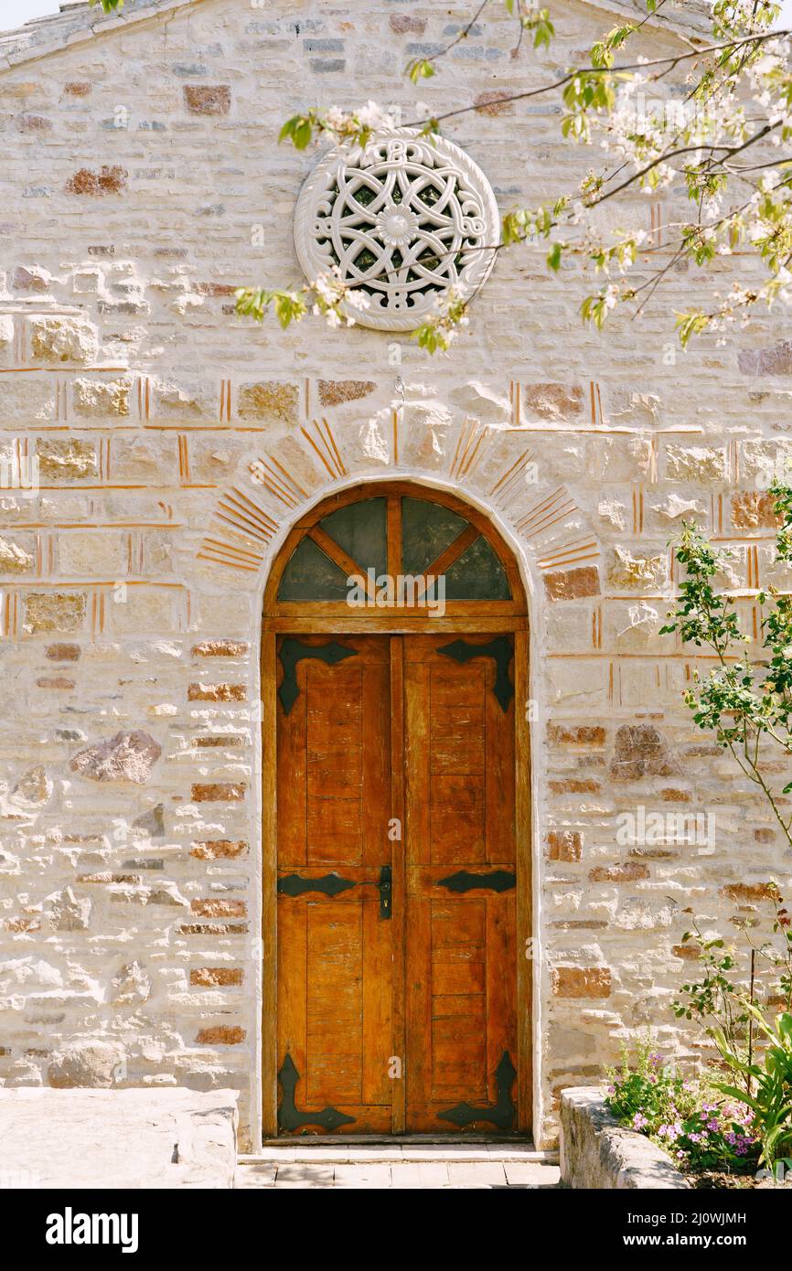 Mur en pierre de l'église Saint-Petka avec une fenêtre rose et une porte en bois.Budva, Monténégro Banque D'Images