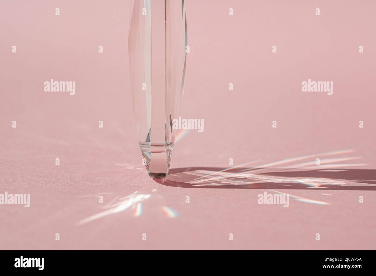 Prisme en cristal avec diffraction de la lumière des couleurs du spectre et réflexion avec lumière tendance et ombres dures sur fond rose. Spectre lumineux Banque D'Images