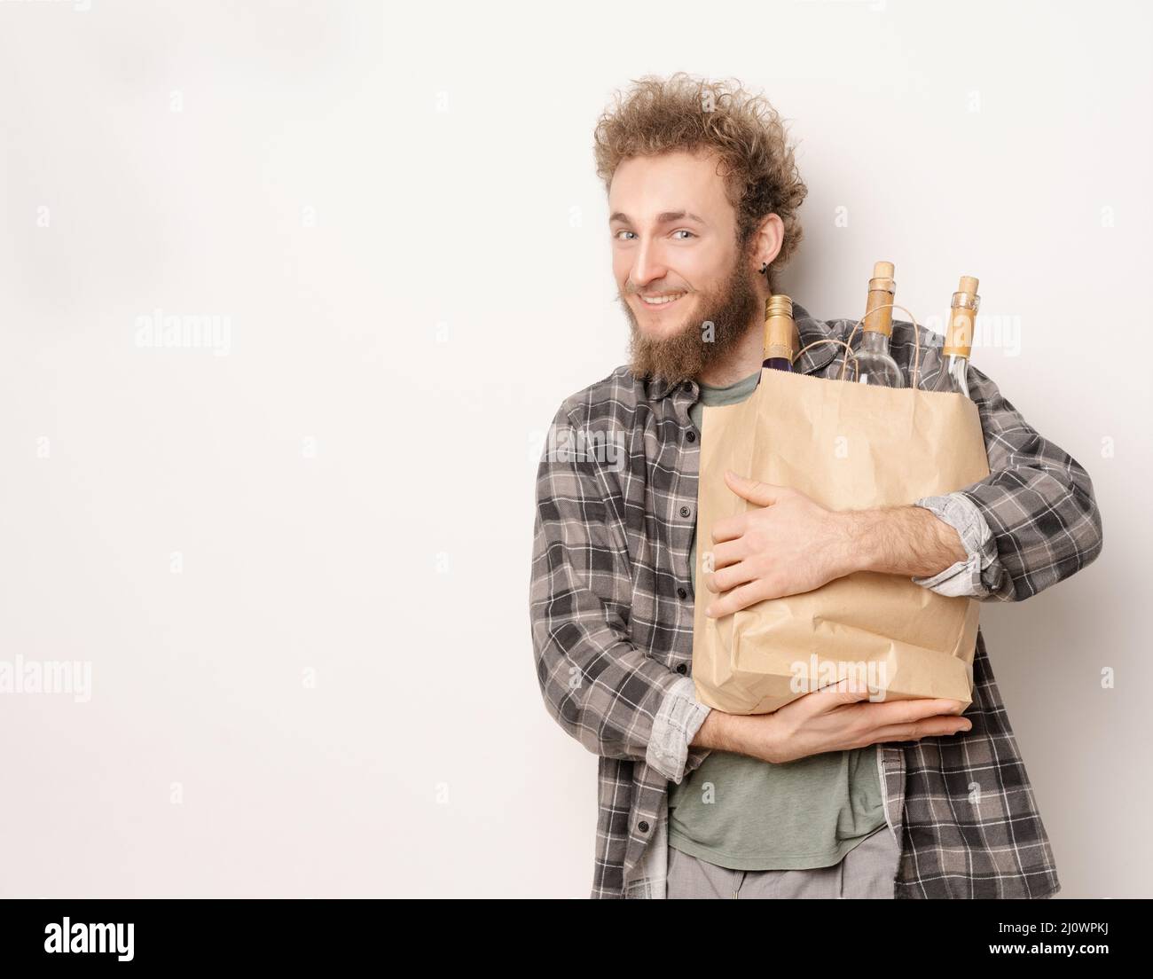 Guy tient un sac en papier avec des bouteilles de vin. Souriant, il regarde dans l'appareil photo. Concept d'un bon moment, une réunion amicale, prepas Banque D'Images