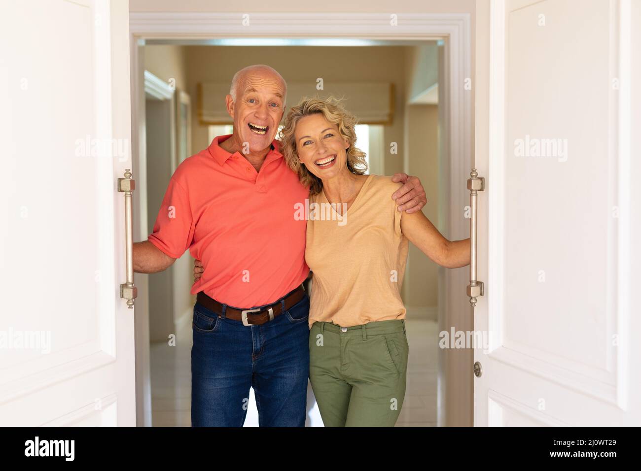 Portrait d'un couple âgé caucasien souriant tout en ouvrant la porte d'entrée de la maison Banque D'Images