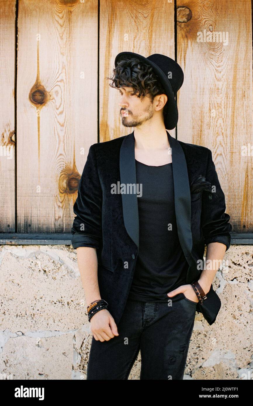 Homme dans un chapeau noir contre un mur en bois Photo Stock - Alamy
