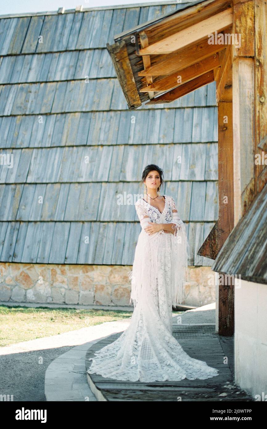 Mariée dans une robe en osier se tient sur le seuil d'une maison en bois Banque D'Images