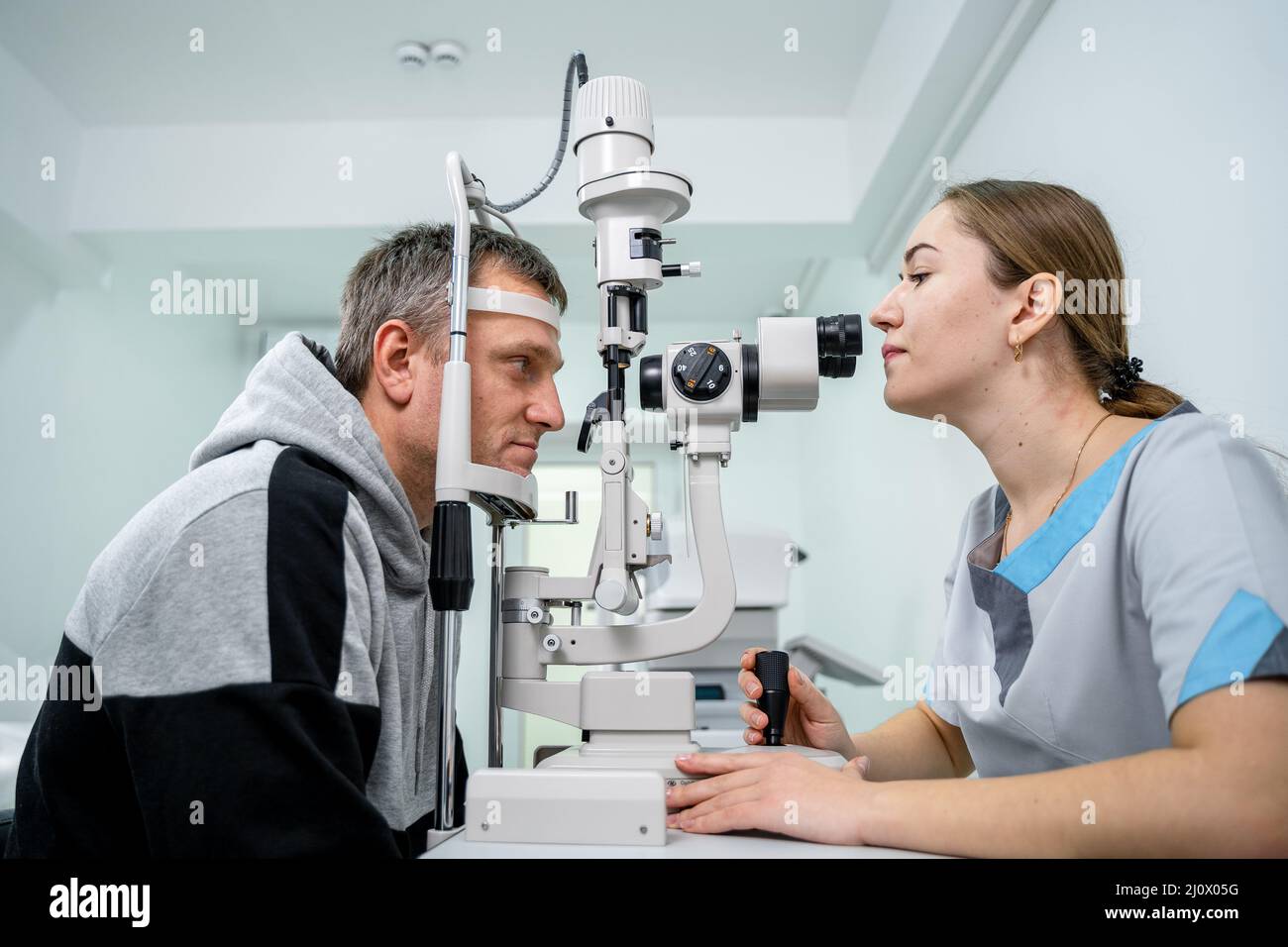Ophtalmologiste et patient testant la vue. Homme faisant un test visuel avec optométriste. Ophtalmologiste utilisant un appareil pour l'examen des yeux Banque D'Images