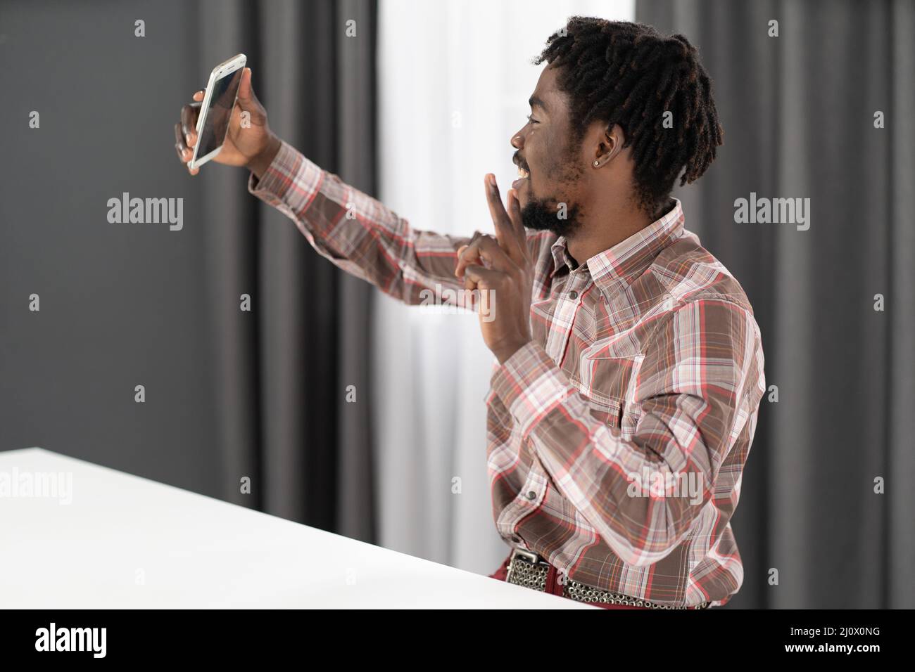 Prendre un selfie ou passer un appel vidéo un jeune afro-américain tient son téléphone dans la main tendue devant lui. Portrait de l'homme heureux g Banque D'Images