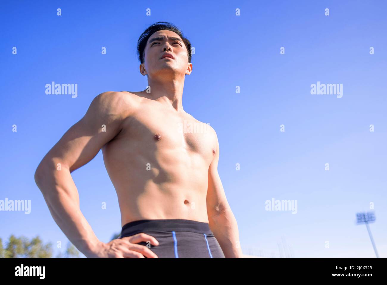 Beau sportif asiatique avec corps musclé sur le stade Banque D'Images