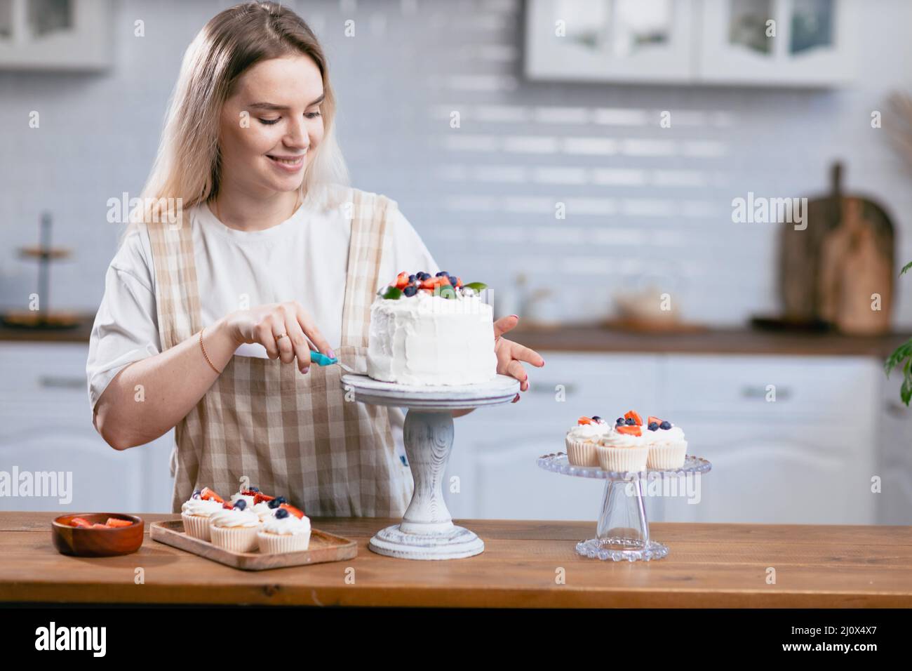 Pâtisserie chef confiserie jeune femme caucasienne avec gâteau sur table de cuisine. Banque D'Images