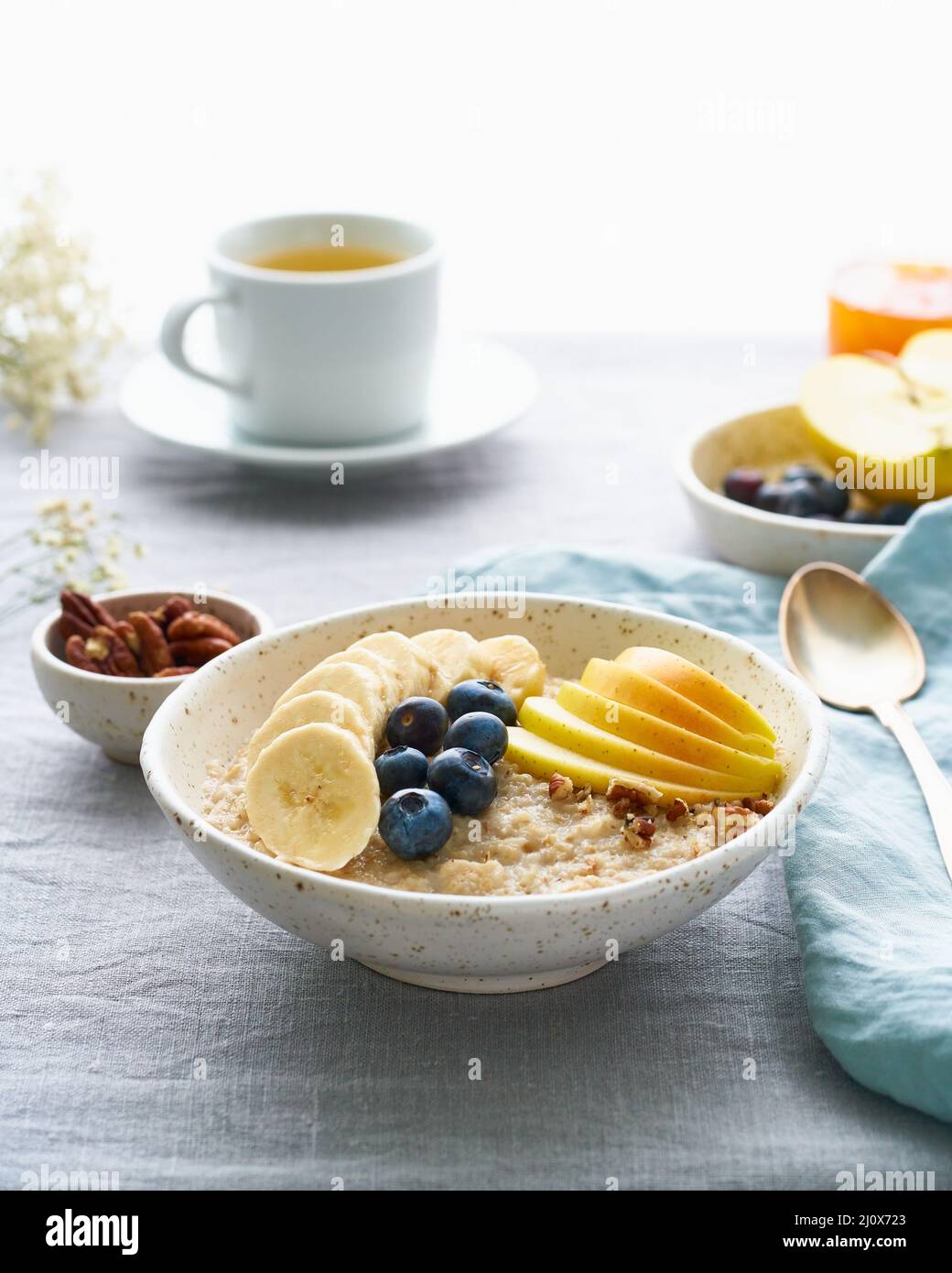 Flocons d'avoine entiers, grand bol de porridge avec banane, bleuets, pomme, noix. Vue latérale, verticale Banque D'Images