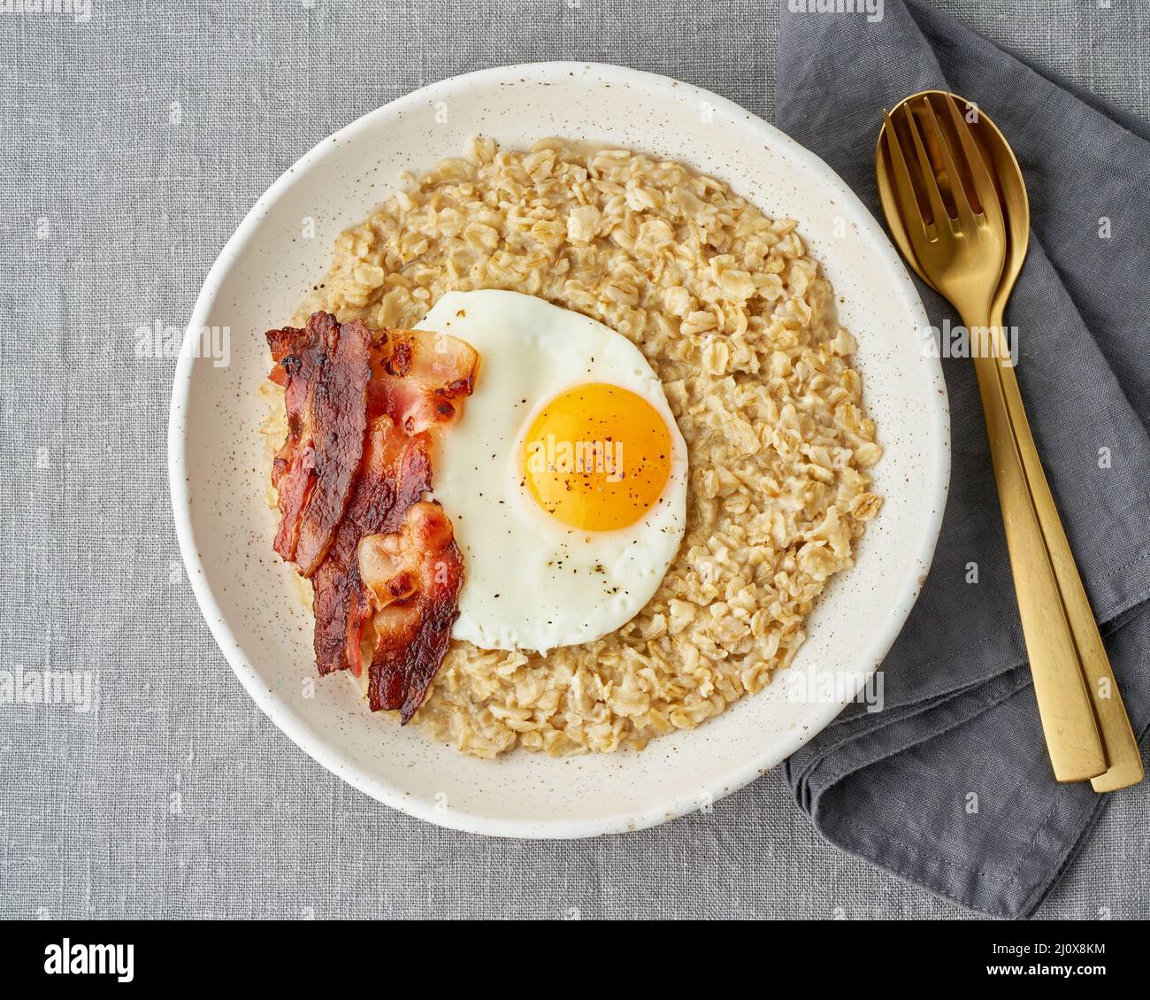 Flocons d'avoine, œufs frits et bacon frit. Copieux petit déjeuner riche en calories, source d'énergie. Banque D'Images