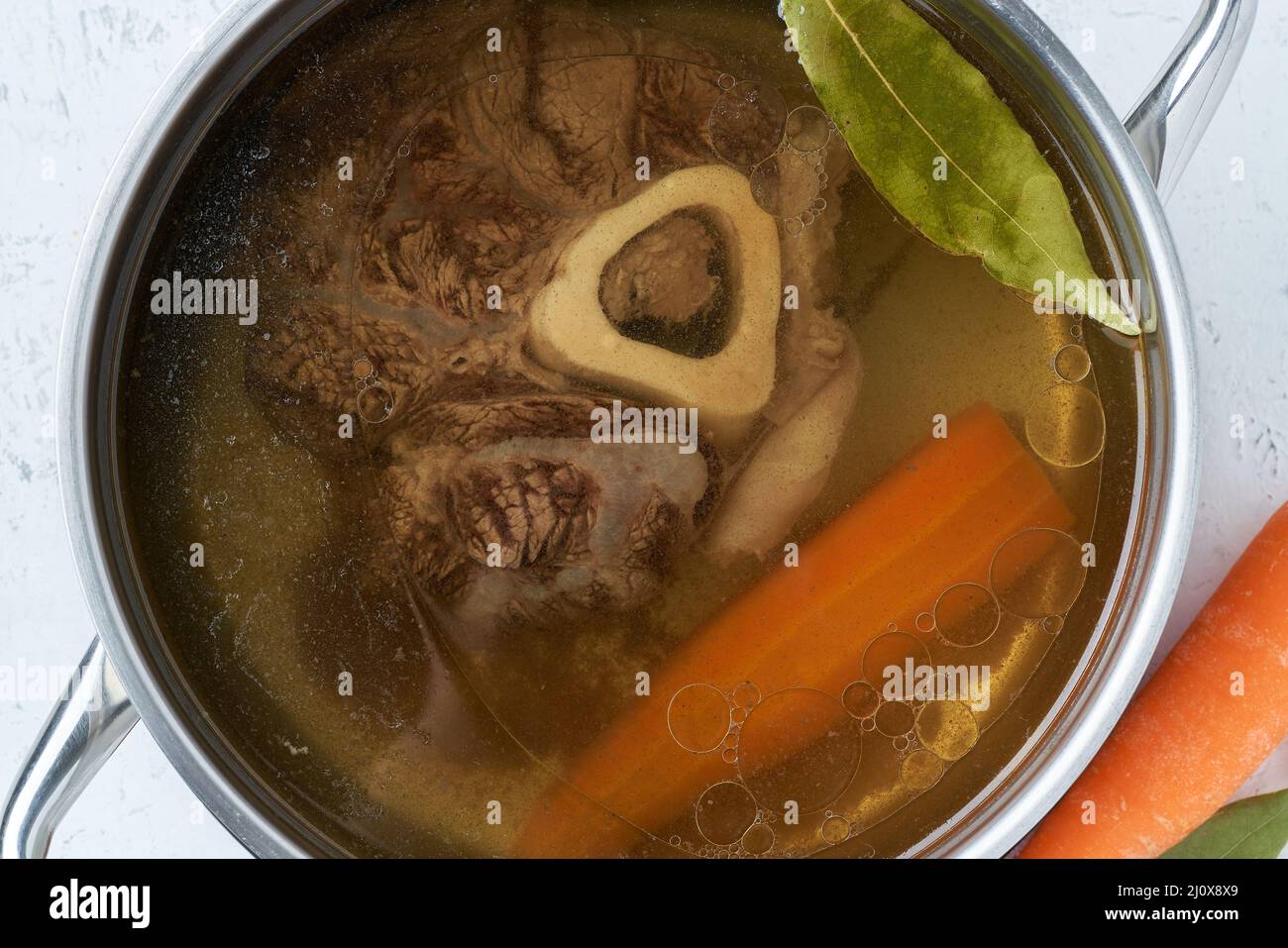 Bouillon de viande de bœuf, l'ossobuco sur l'os, soupe riche dans une casserole, longue cuisson lente. Banque D'Images Bouillon de viande de bœuf, l'ossobuco sur l'os, soupe riche dans une casserole, longue cuisson lente. Banque D'Images