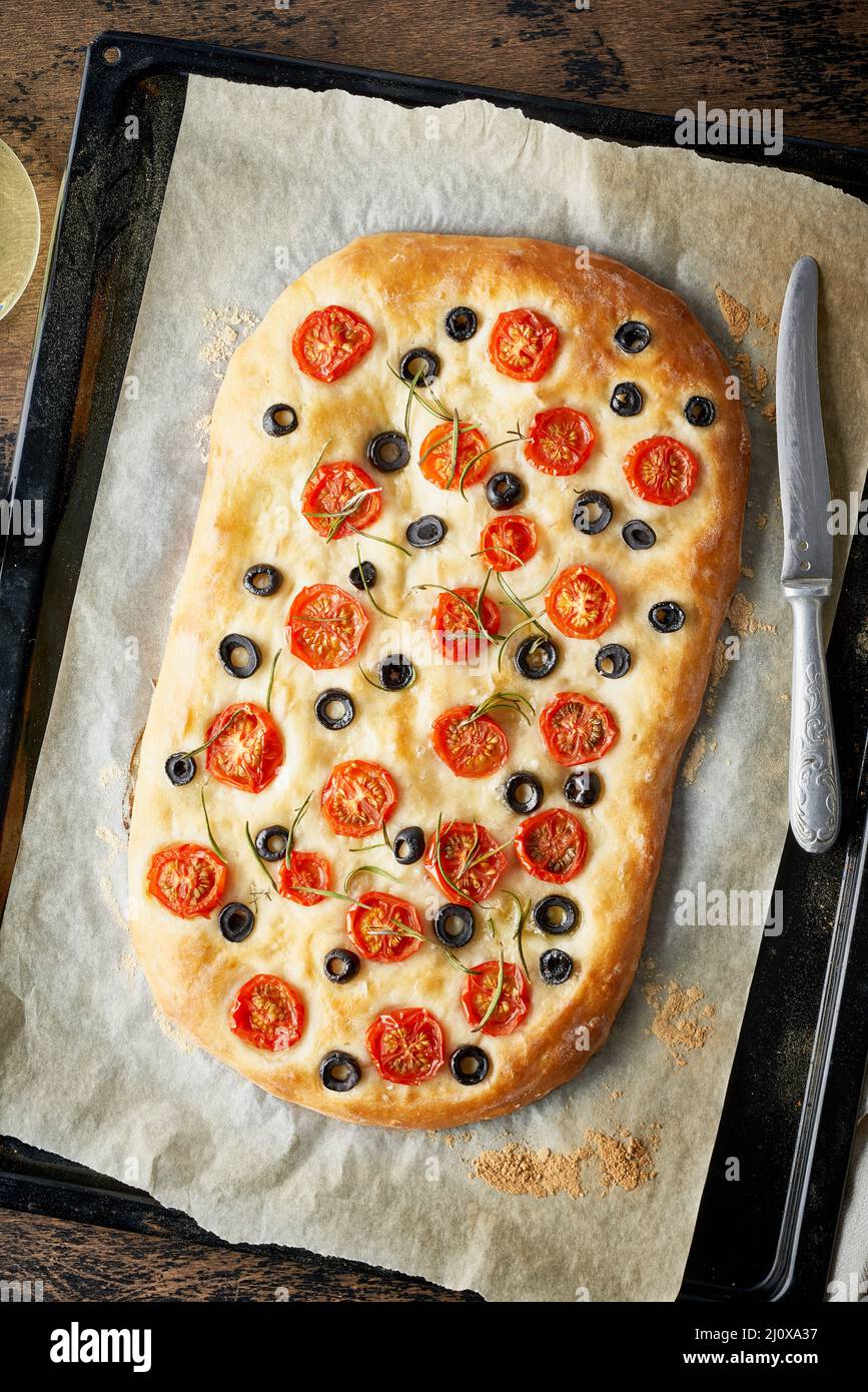 Focaccia, pizza, pain plat italien avec tomates, olives et romarin sur le plateau Banque D'Images