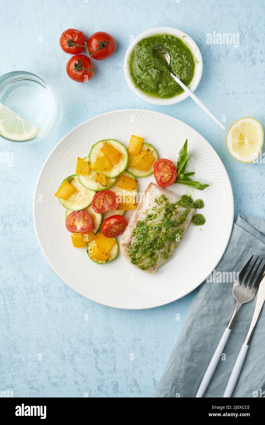 Dîner de keto avec poisson blanc. Filet de morue cuit au four, perche de brochet avec légumes et sauce pesto Banque D'Images