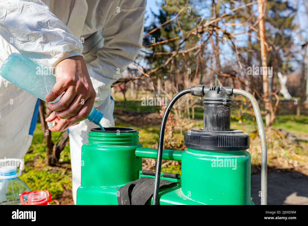 L'agriculteur prépare un mélange d'eau et de solutions botaniques de  pesticides dans un pulvérisateur de sac à couteaux en plastique pour  pulvériser des arbres fruitiers dans le verger afin des protéger Photo