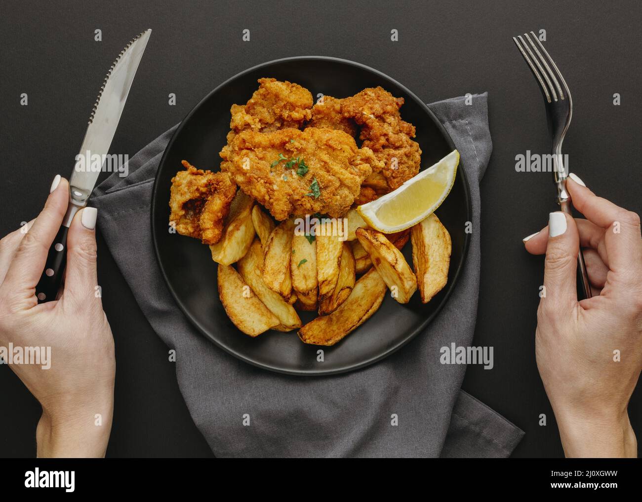 Vue de dessus plaque Fish chips avec femme tenant des couverts Banque D'Images