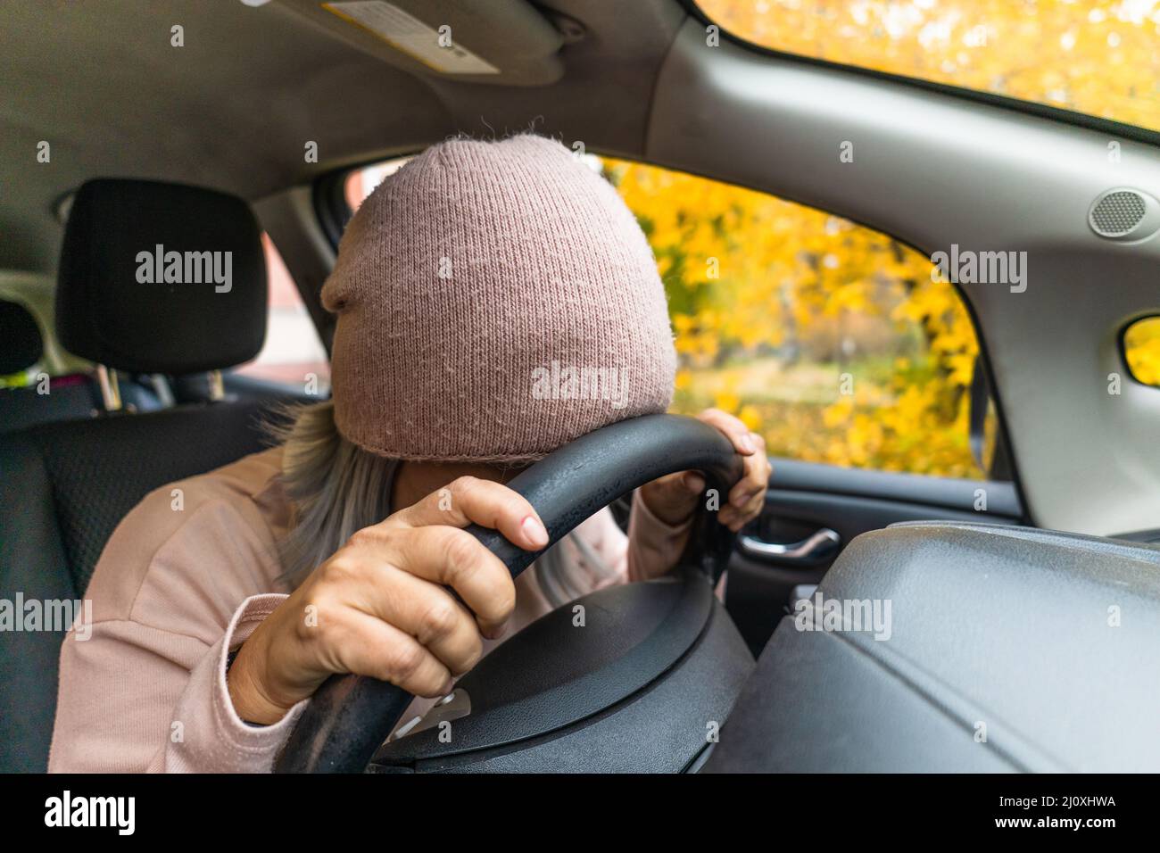 Une femme asiatique mûre s'est endormie à la voiture sur un volant. Une femme asiatique qui dormait épuisée dormait dans la voiture. Blond moyen Banque D'Images