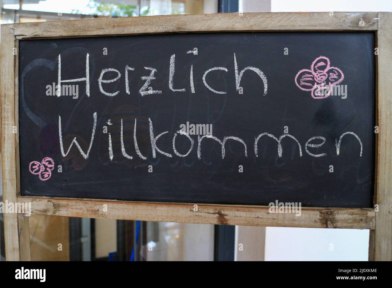 Tableau noir extérieur avec le texte allemand 'Herzlich willkommen' qui se traduit en 'Heartly Welcome' en langue anglaise Banque D'Images Tableau noir extérieur avec le texte allemand 'Herzlich willkommen' qui se traduit en 'Heartly Welcome' en langue anglaise Banque D'Images