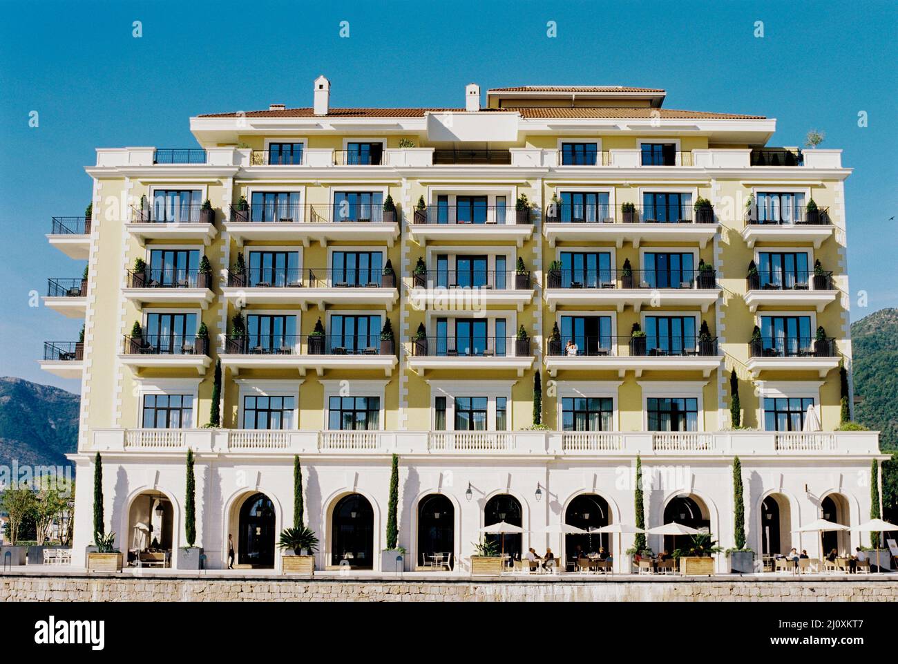 Façade de l'hôtel Regent avec des montagnes en arrière-plan à Porto. Monténégro Banque D'Images