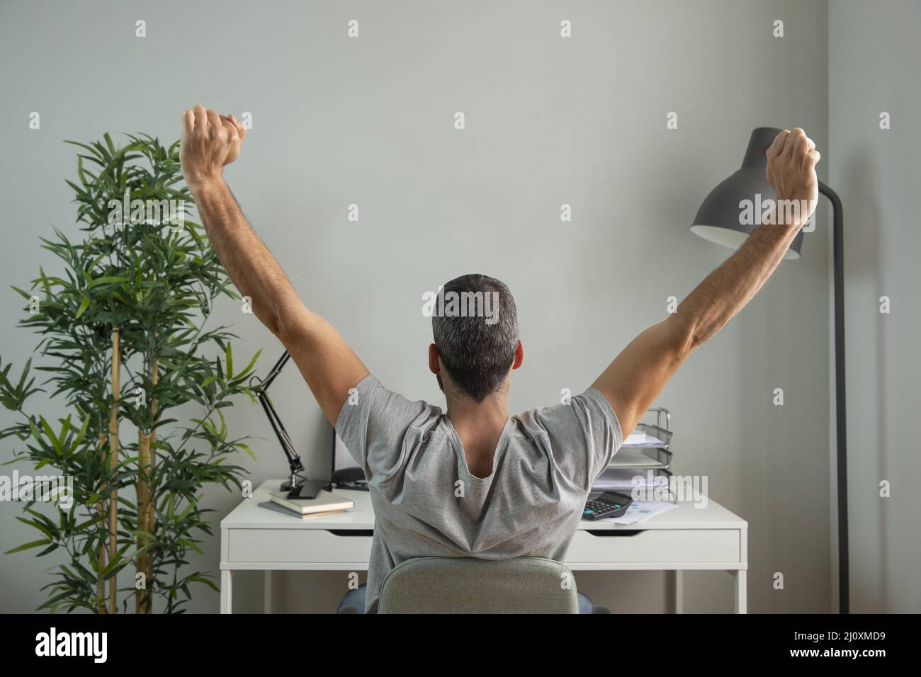 Homme de vue arrière qui étire ses bras tout en travaillant de la maison. Concept de photo de haute qualité Banque D'Images